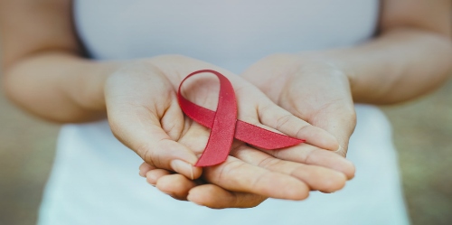 Hands holding a red HIV Ribbon